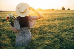 Beautiful,Woman,In,Hat,With,Wildflowers,Bouquet,Standing,In,Barley